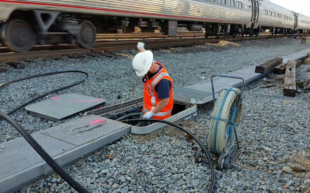 Technicians pulling a 50-pair copper telephone cable along a rail corridor